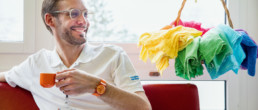 Palliativmediziner Dr. med. Manuel Jungi mit farbigen Tüchern im Hintergrund.