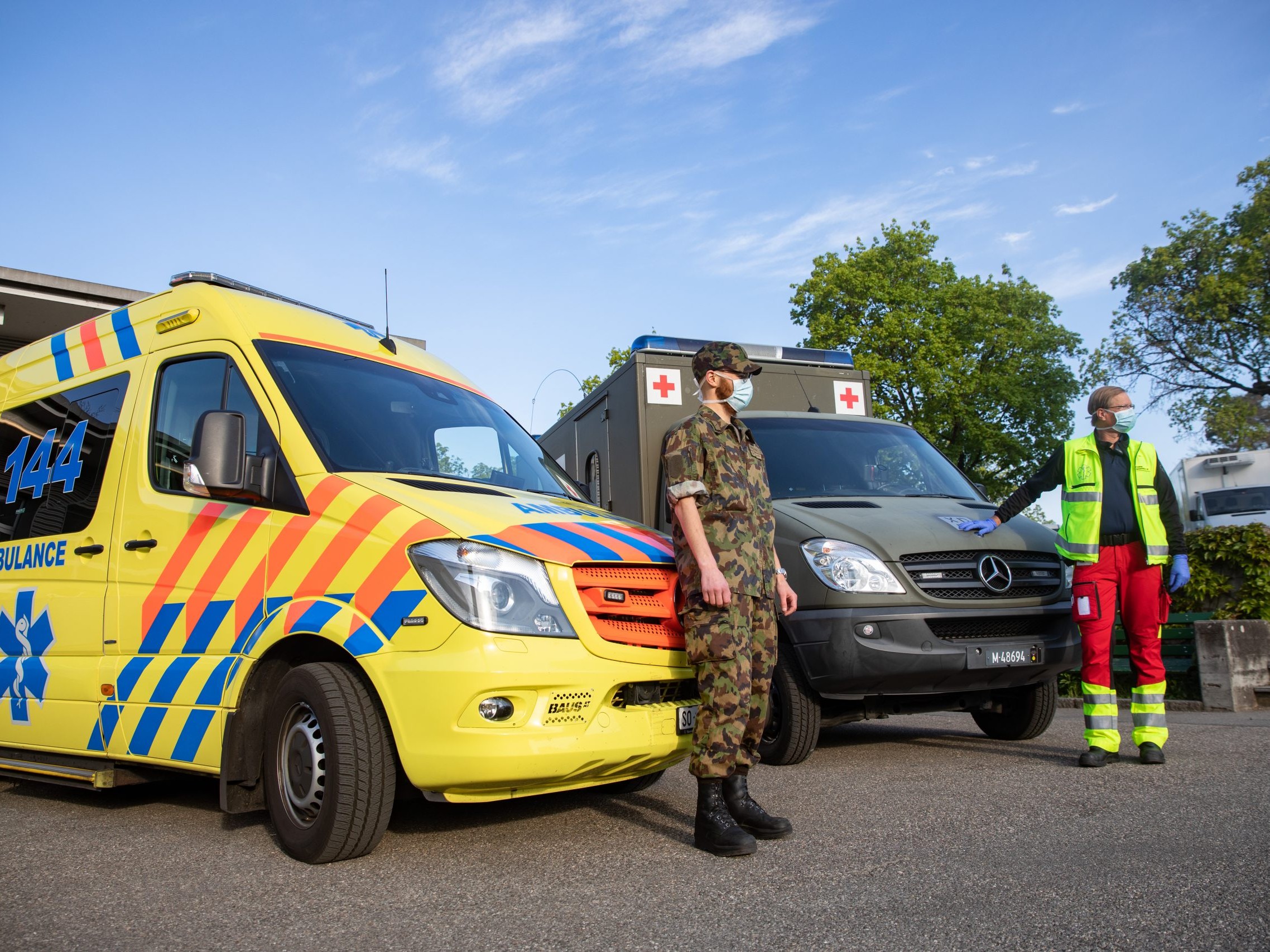 Ein Armee-Angehöriger und ein Rettungssanitäter stehen vor zwei Rettungsfahrzeugen