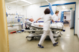 Zwei Pflegerinnen schieben einen Patienten im Bett