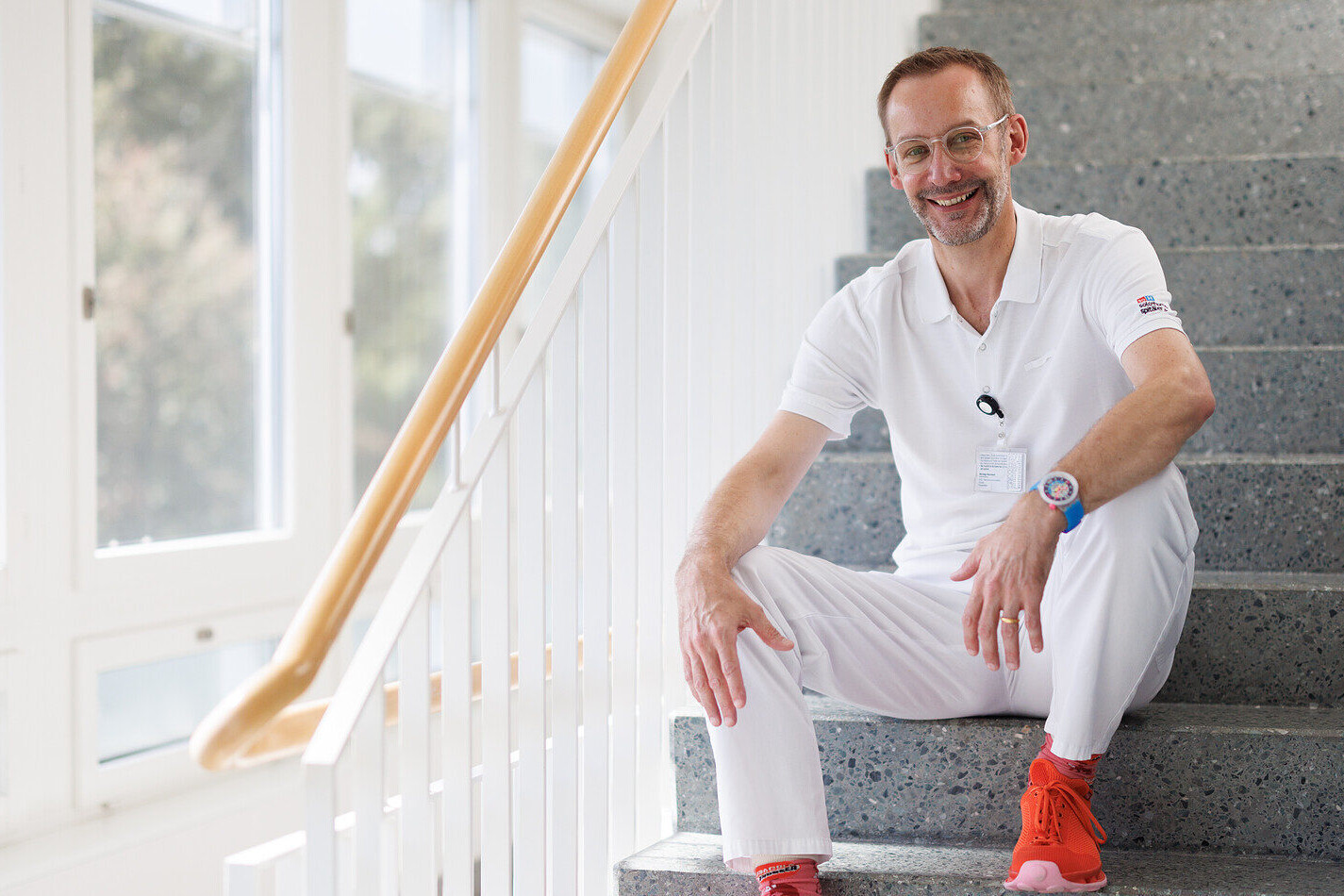 Arzt sitzt auf der Treppe und schaut in die Kamera